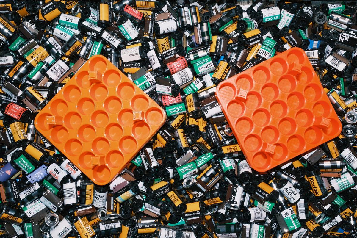 Two empty orange film-processing racks lying on a pile of spent 35mm film canisters